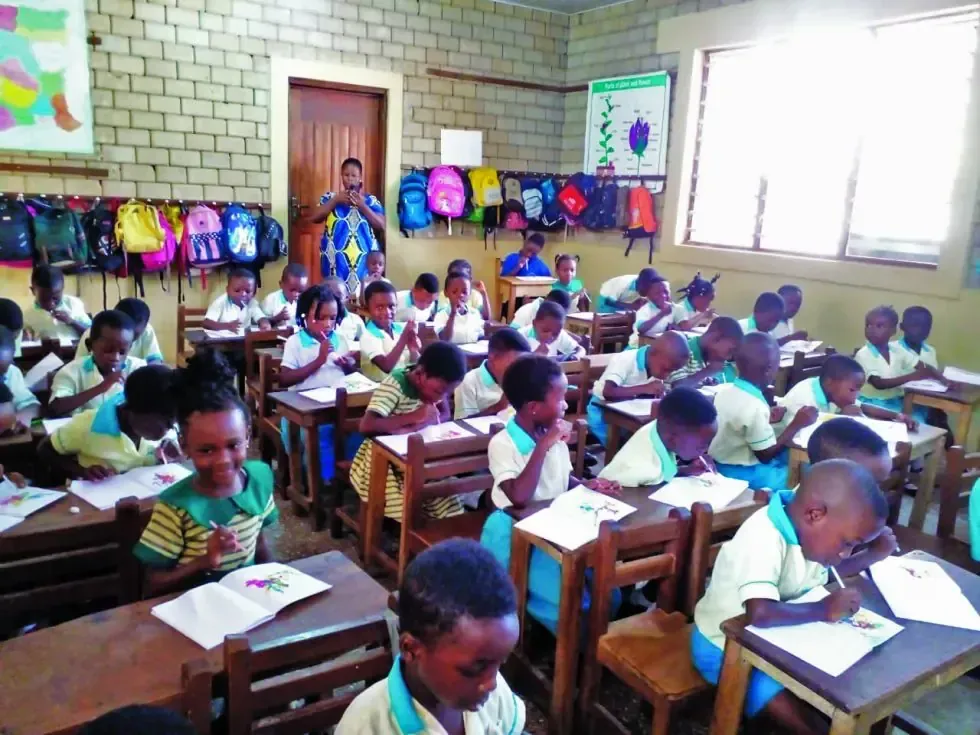A large group of children are sitting at their desks in a classroom