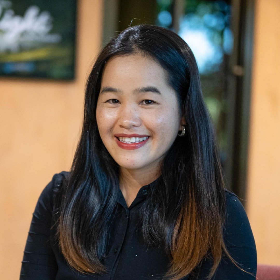 A woman with long black hair is smiling for the camera while wearing a black shirt.