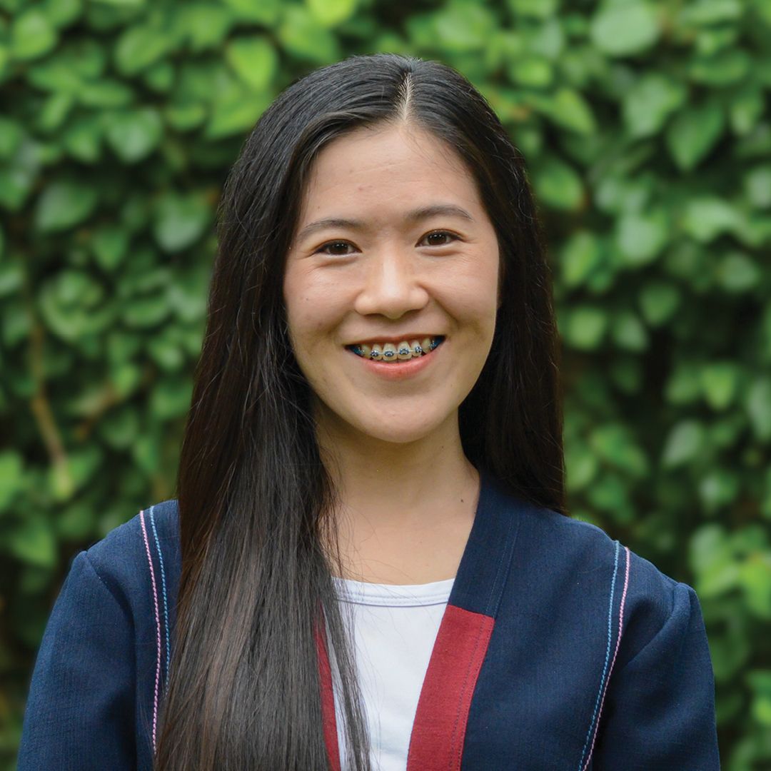 A woman with long hair is smiling and wearing a white shirt.