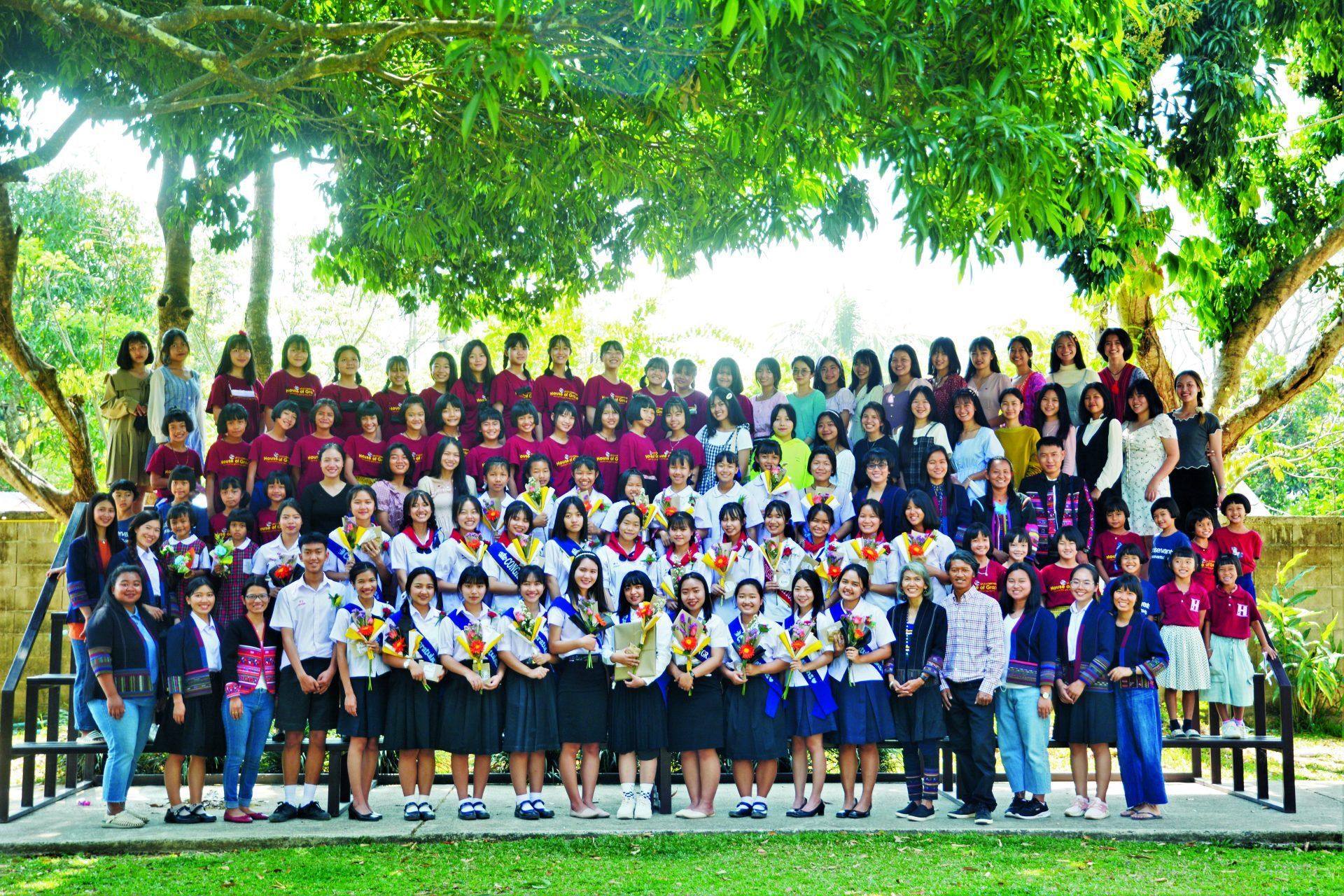 A large group of people are posing for a picture under a tree.