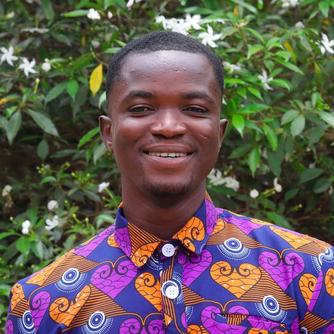 A man wearing a purple and orange shirt is smiling for the camera.