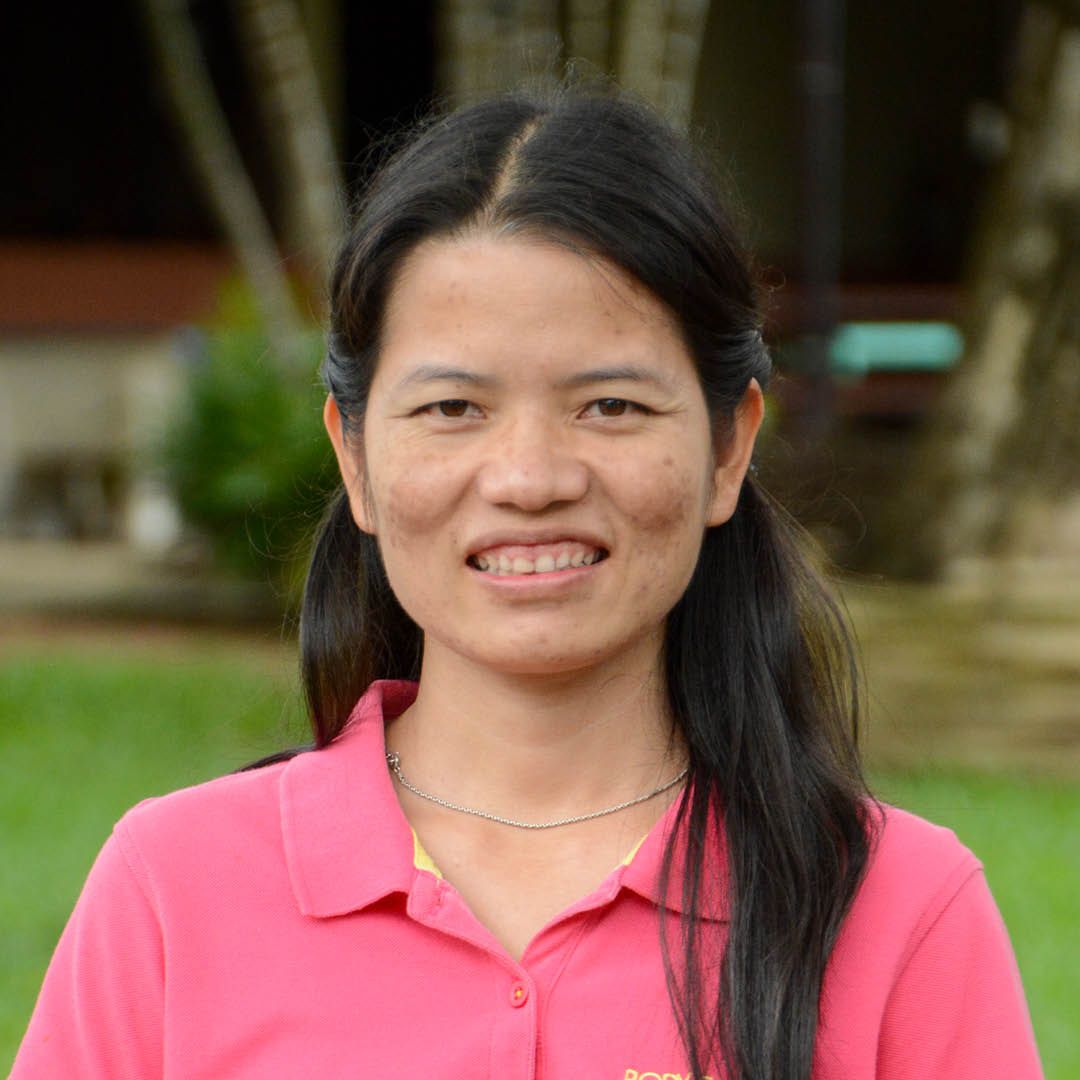 A woman in a pink shirt is smiling for the camera.