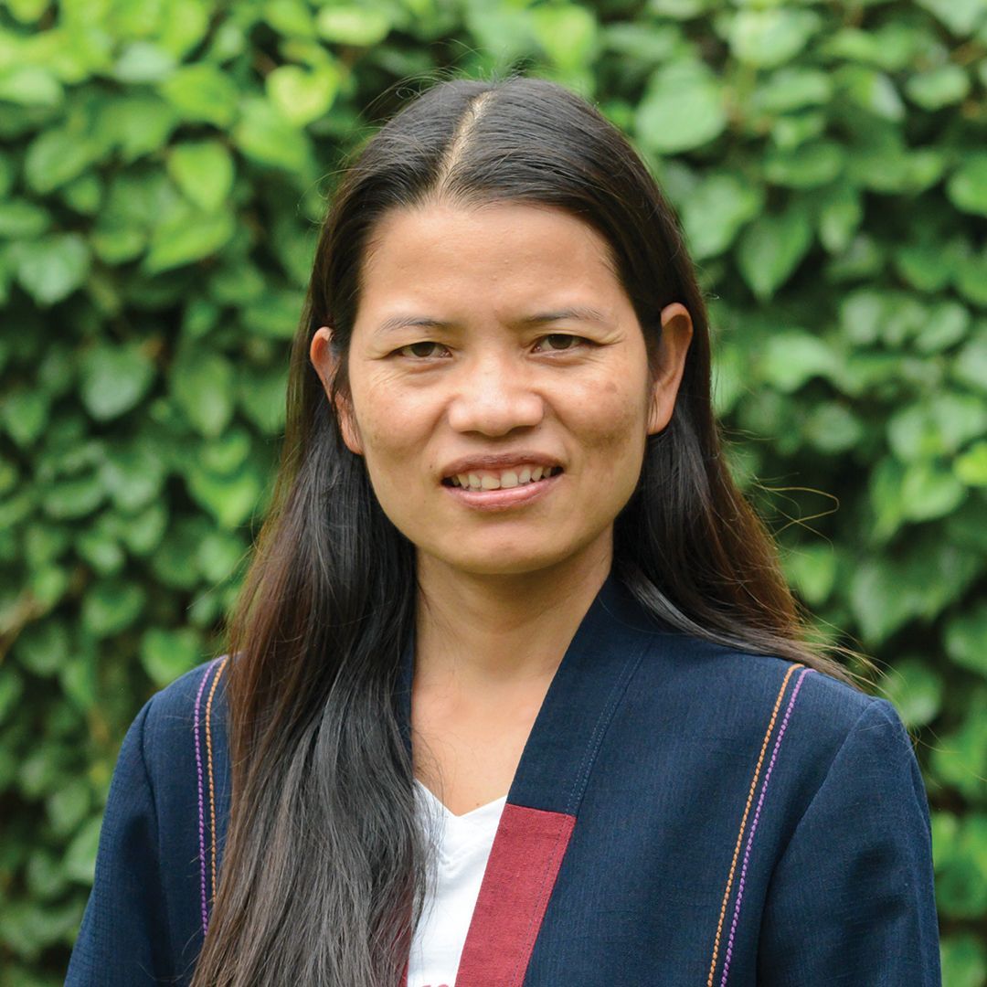 A woman in a pink shirt is smiling for the camera.