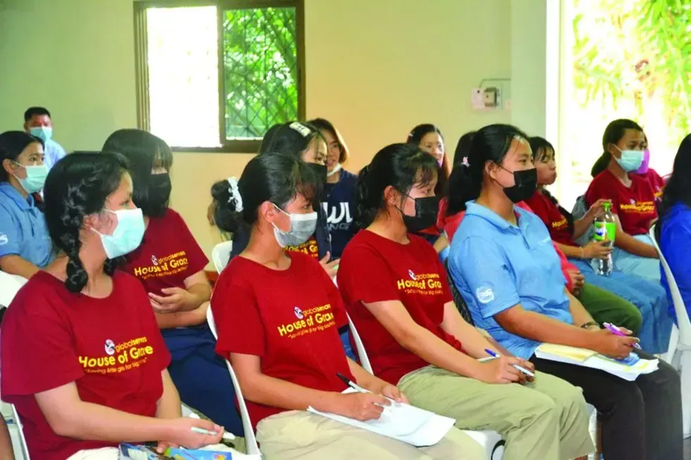 A group of people wearing masks are sitting in a room.