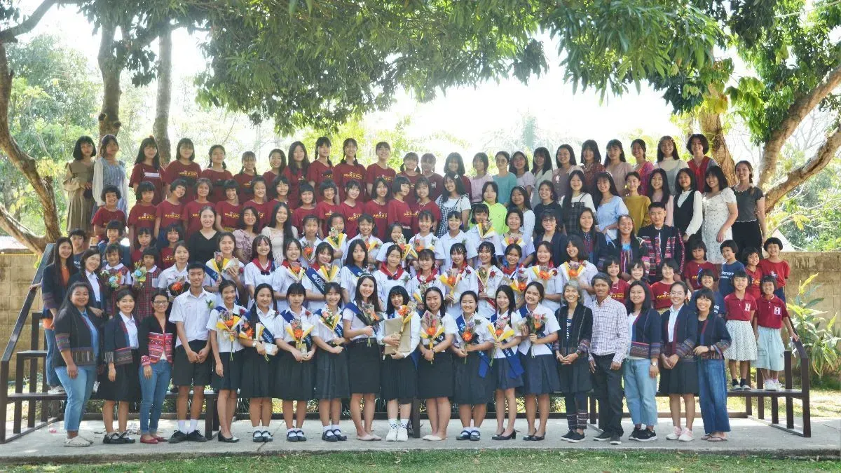 A large group of people are posing for a picture under a tree.