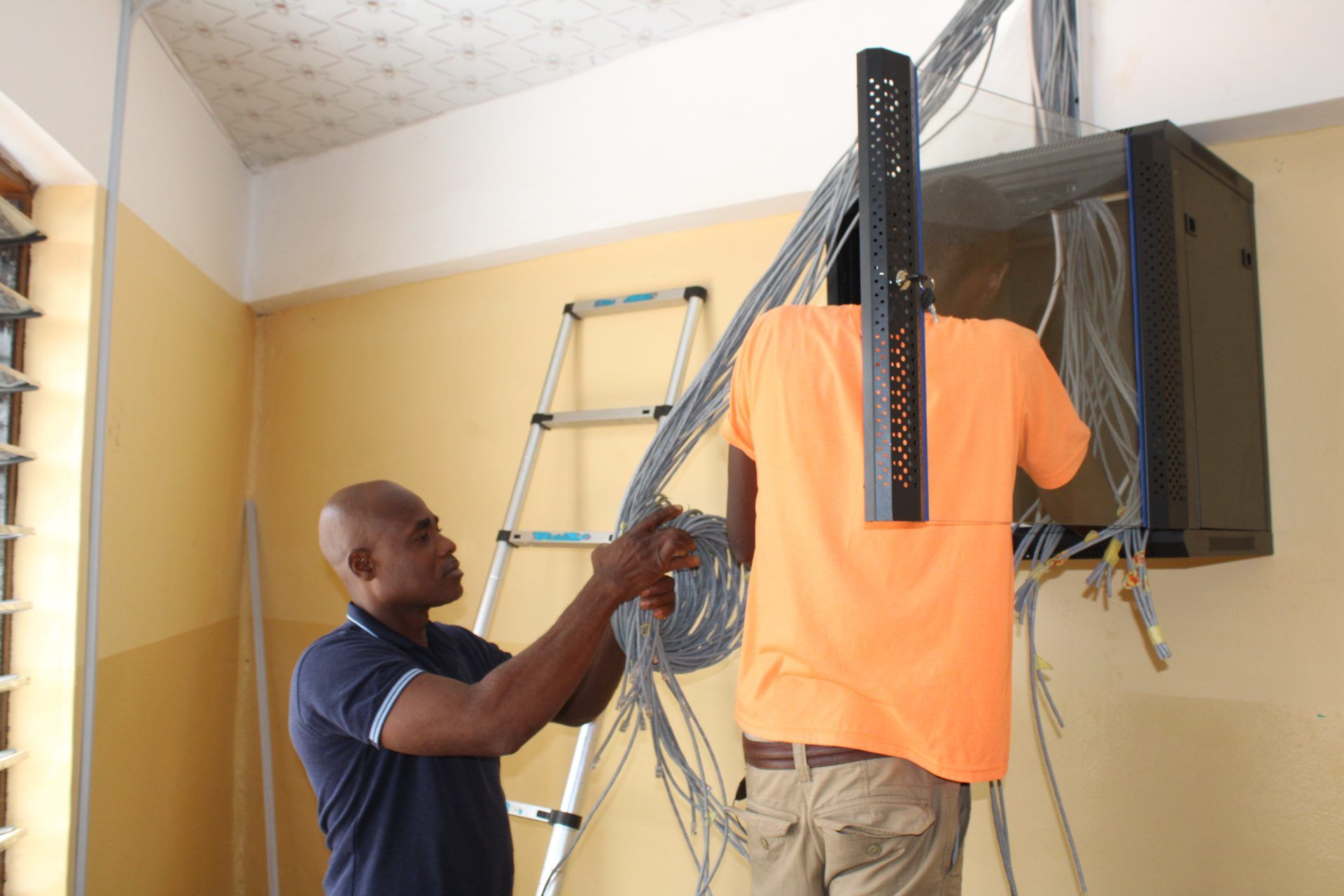 Two men are working on a server in a room