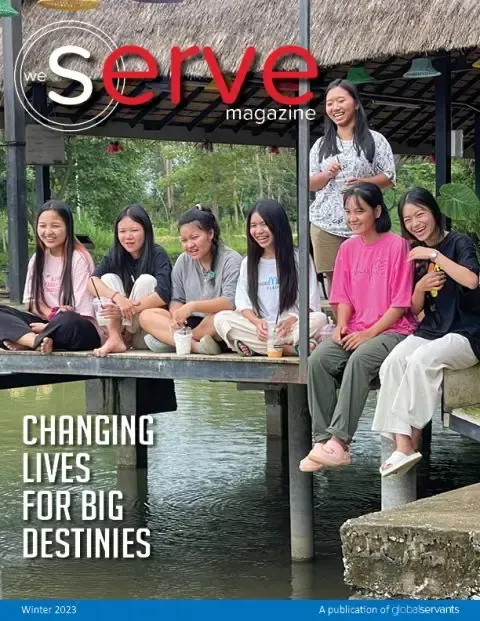 A group of young women are sitting on a dock.