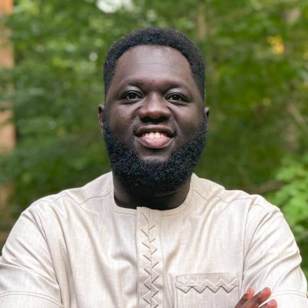 A man with a beard is smiling for the camera with his arms crossed.