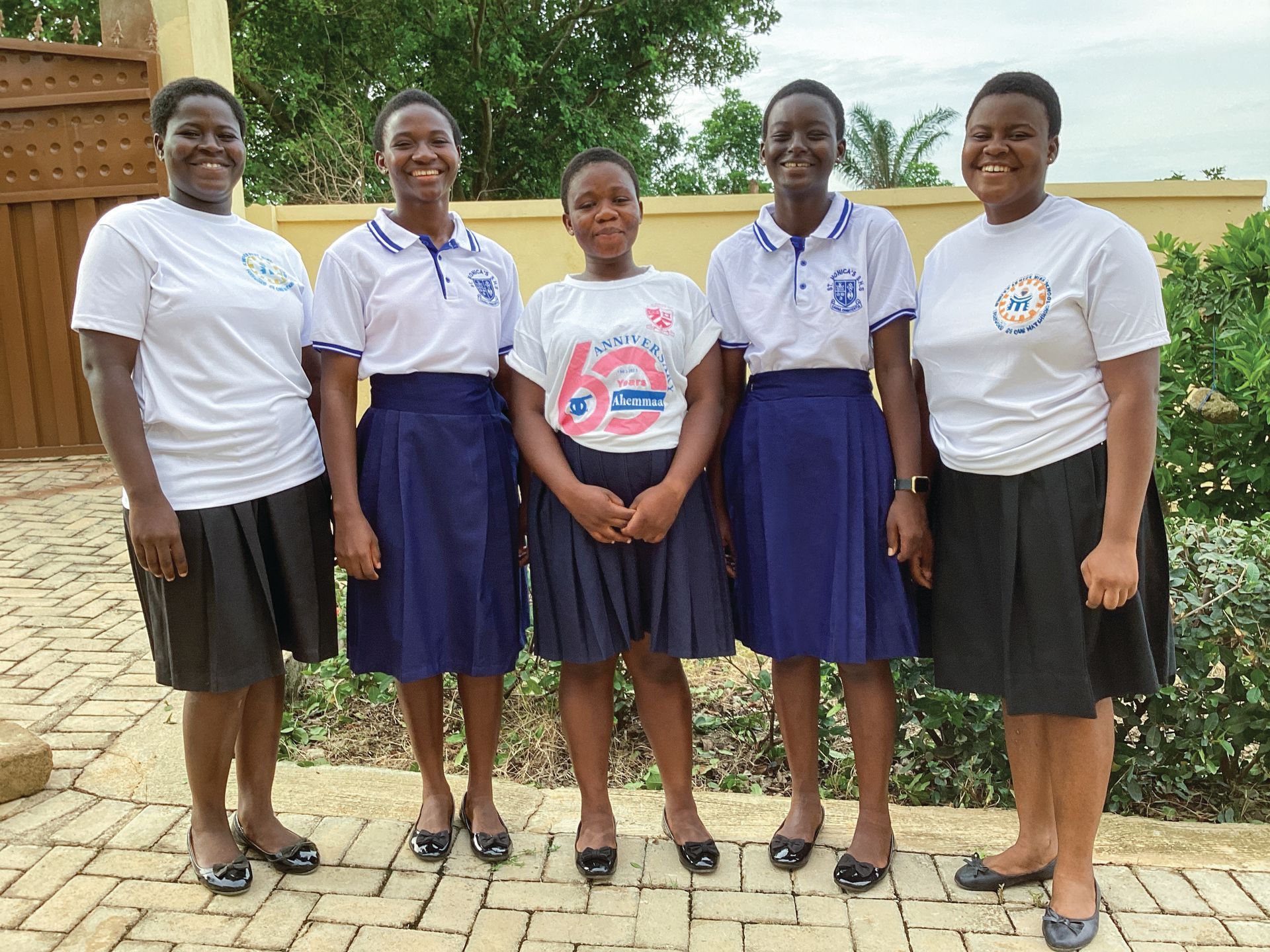 A group of women standing next to each other on a brick sidewalk.