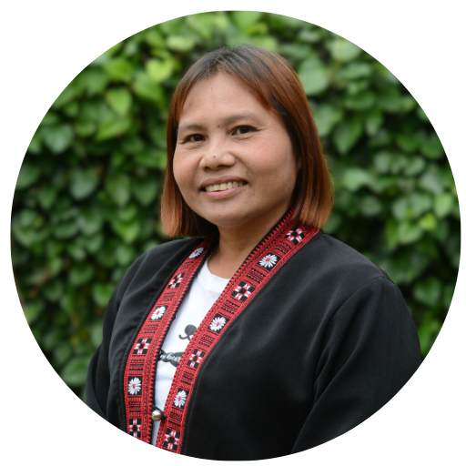 A woman is smiling for the camera in front of a bush.