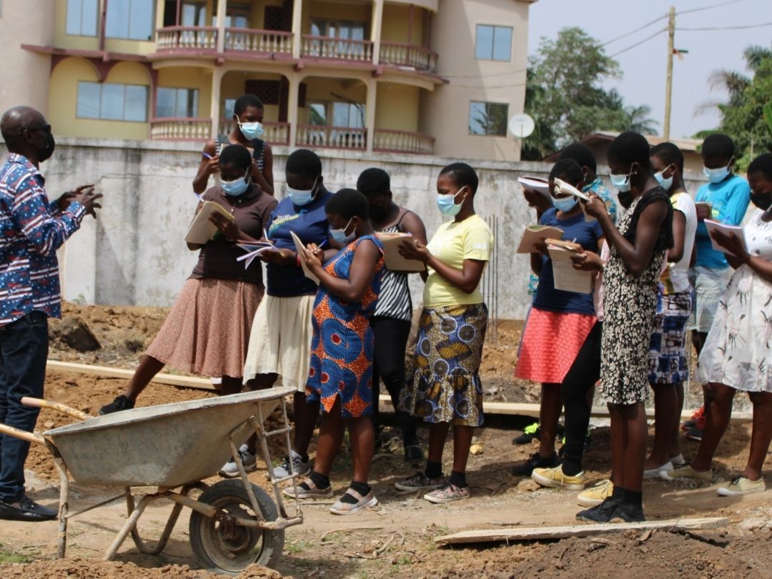 A group of people wearing face masks are standing around a wheelbarrow.