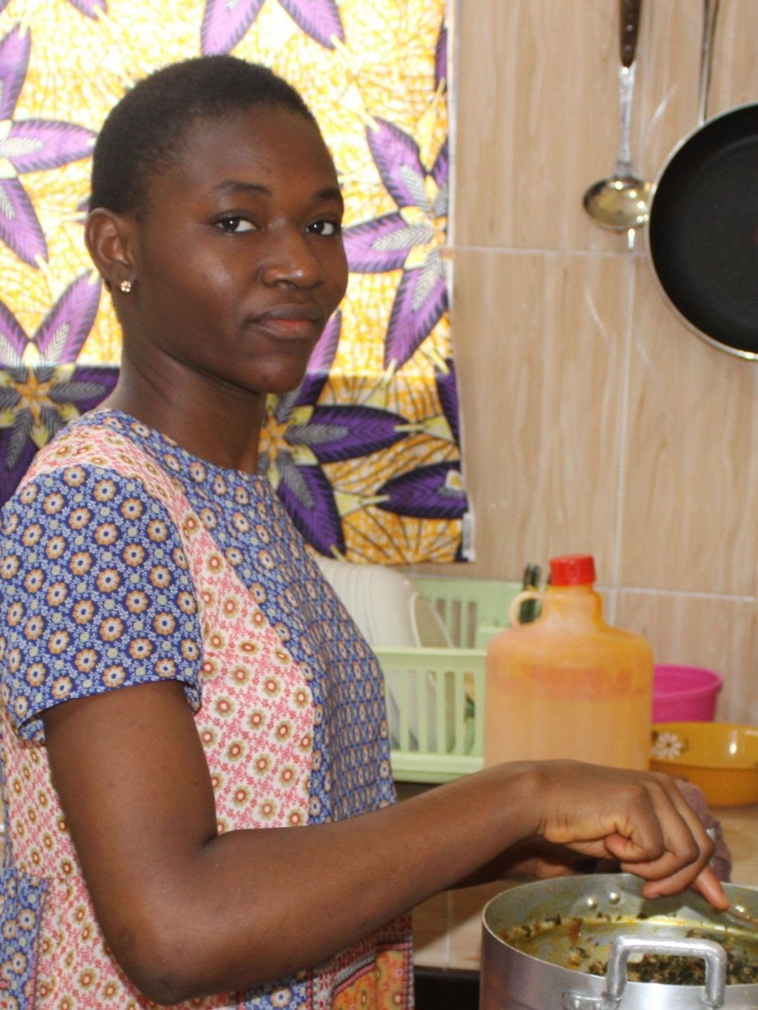 A woman in a blue and pink dress is cooking in a kitchen