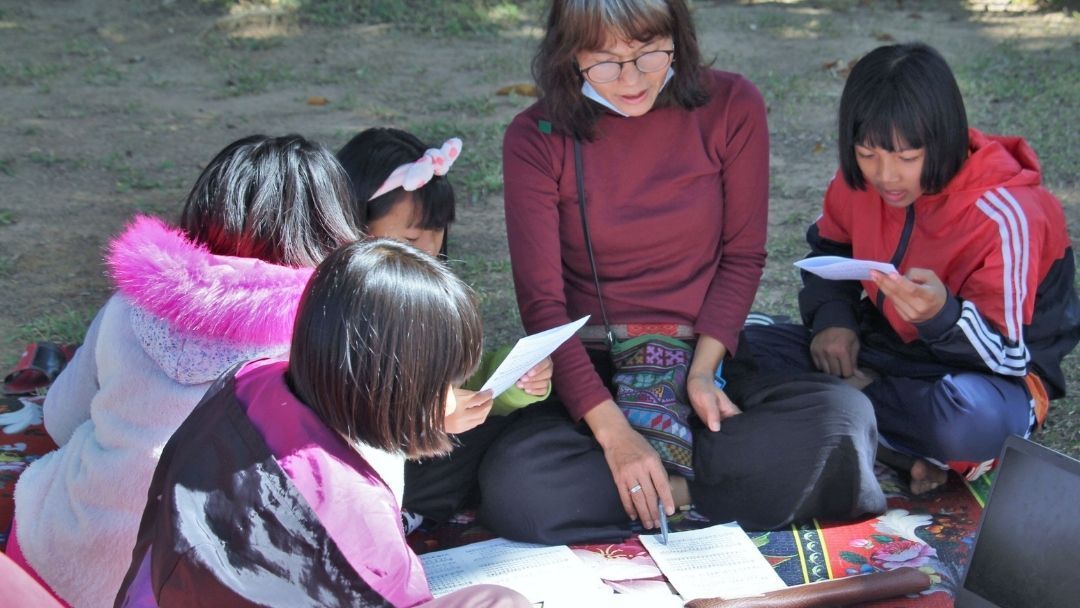 A group of people are sitting on the ground reading books.