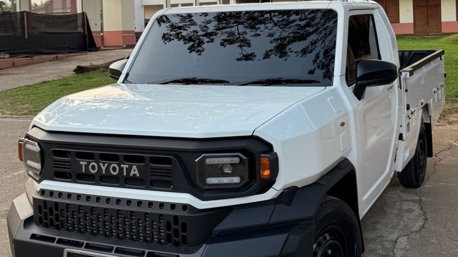 White Toyota pickup truck with black grille and headlights, parked outdoors.