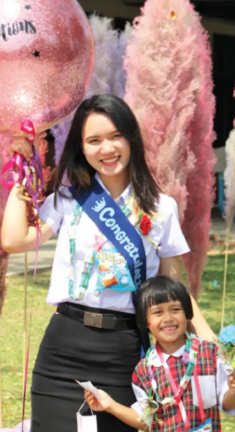 A woman wearing a sash that says congratulations is standing next to a little girl.