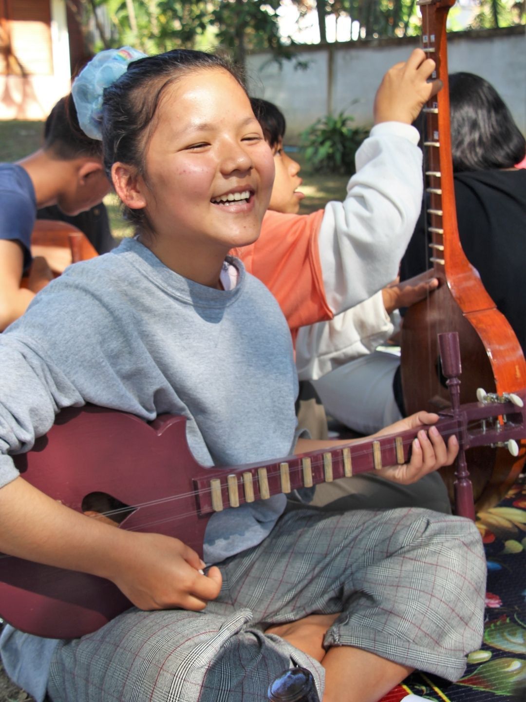 A girl is smiling while playing a guitar