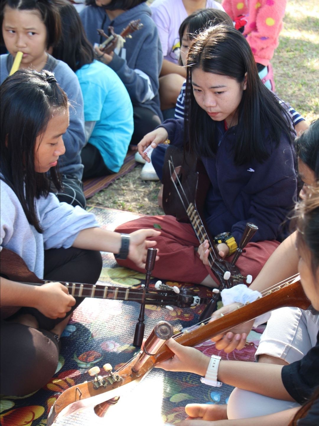 A group of young girls are sitting on the ground playing guitars