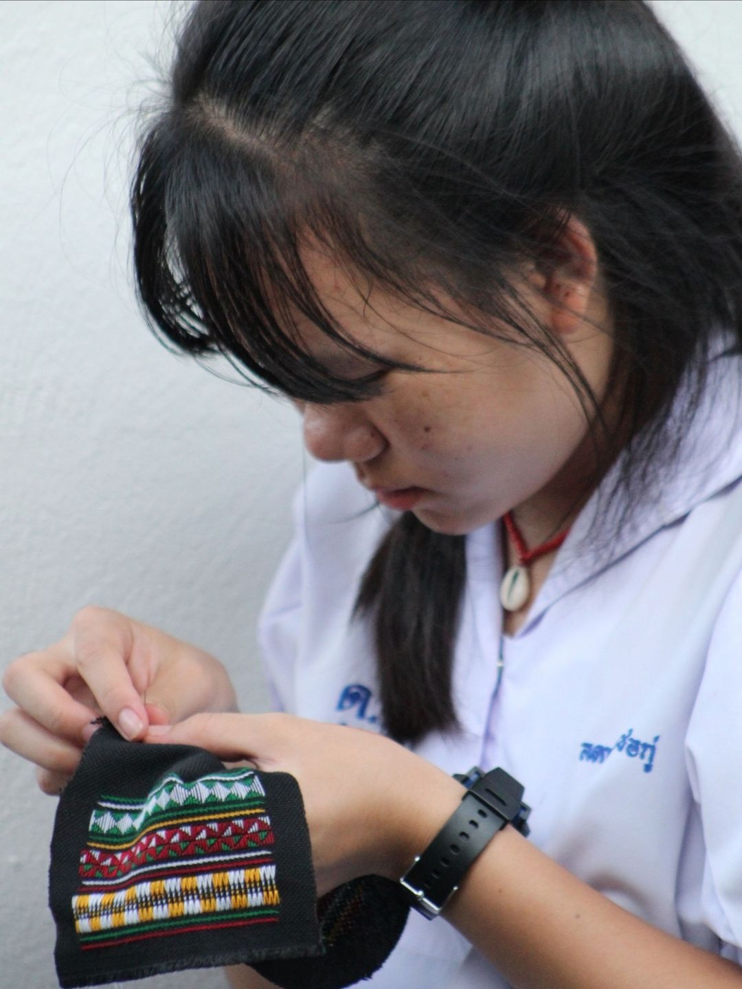 A girl wearing a watch and a white shirt with the letter m on it