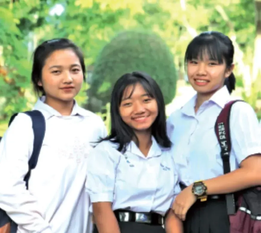Three girls are posing for a picture with one wearing a watch that says ' nikon ' on it