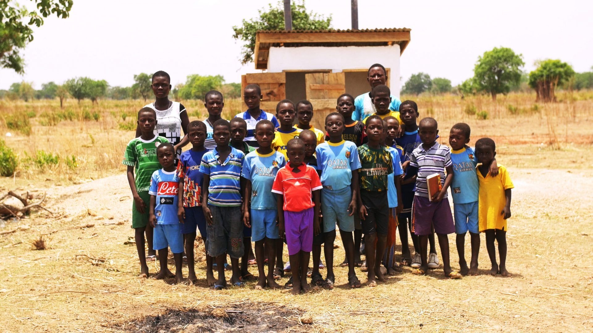 A group of children are posing for a picture in a field.