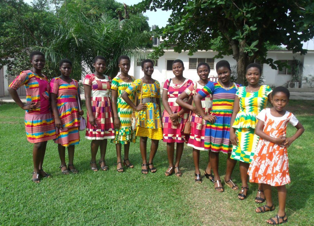 A group of young girls in colorful dresses are posing for a picture