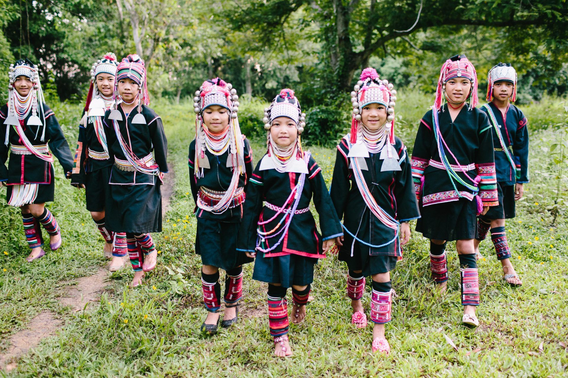 A group of children in traditional costume are walking in a field.