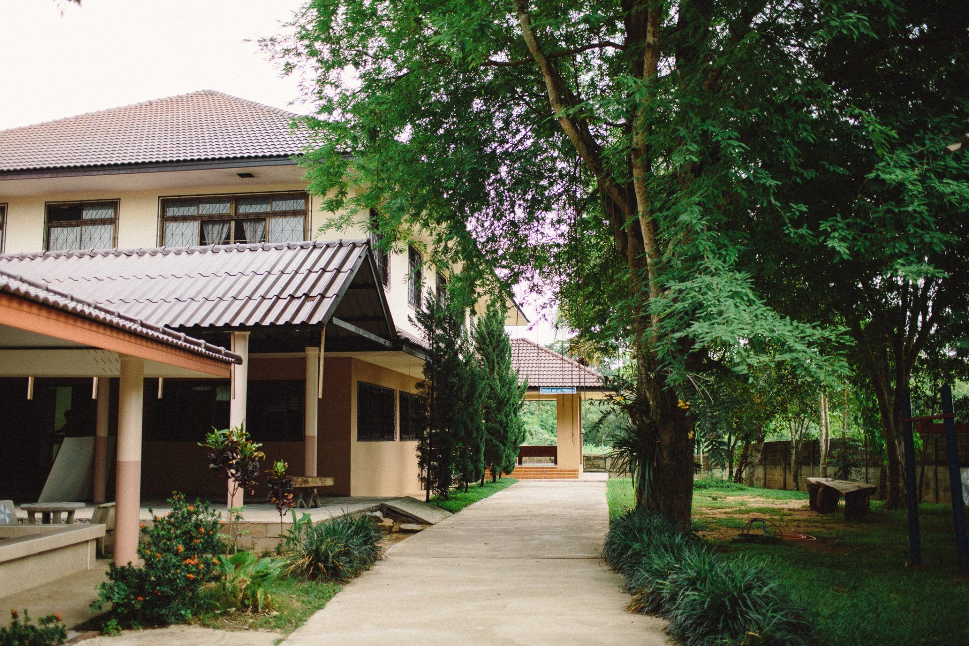 A house with a walkway leading to it surrounded by trees