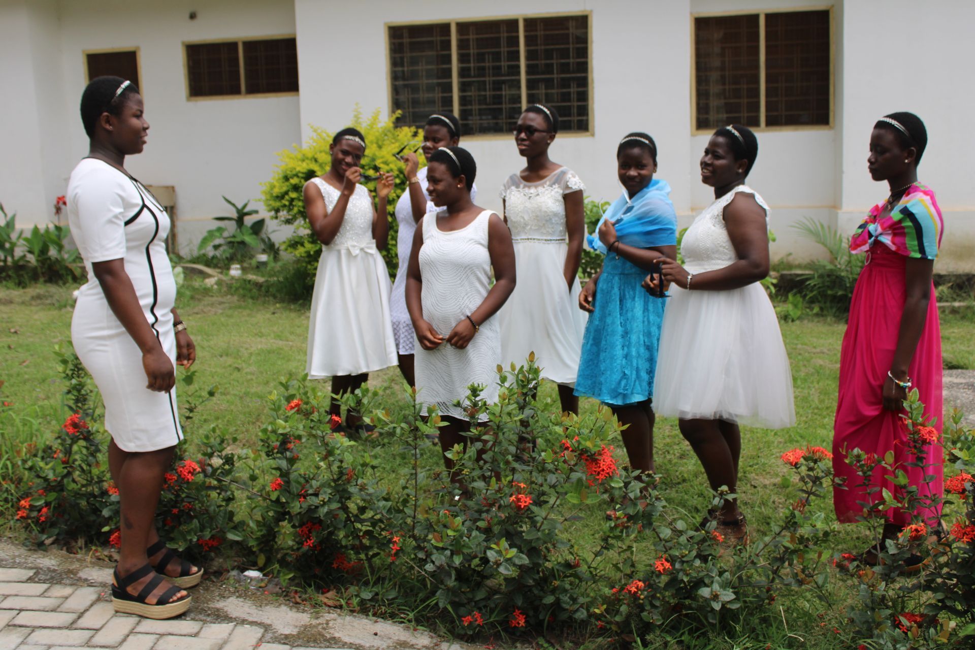 A group of women in white dresses are standing in front of a building.