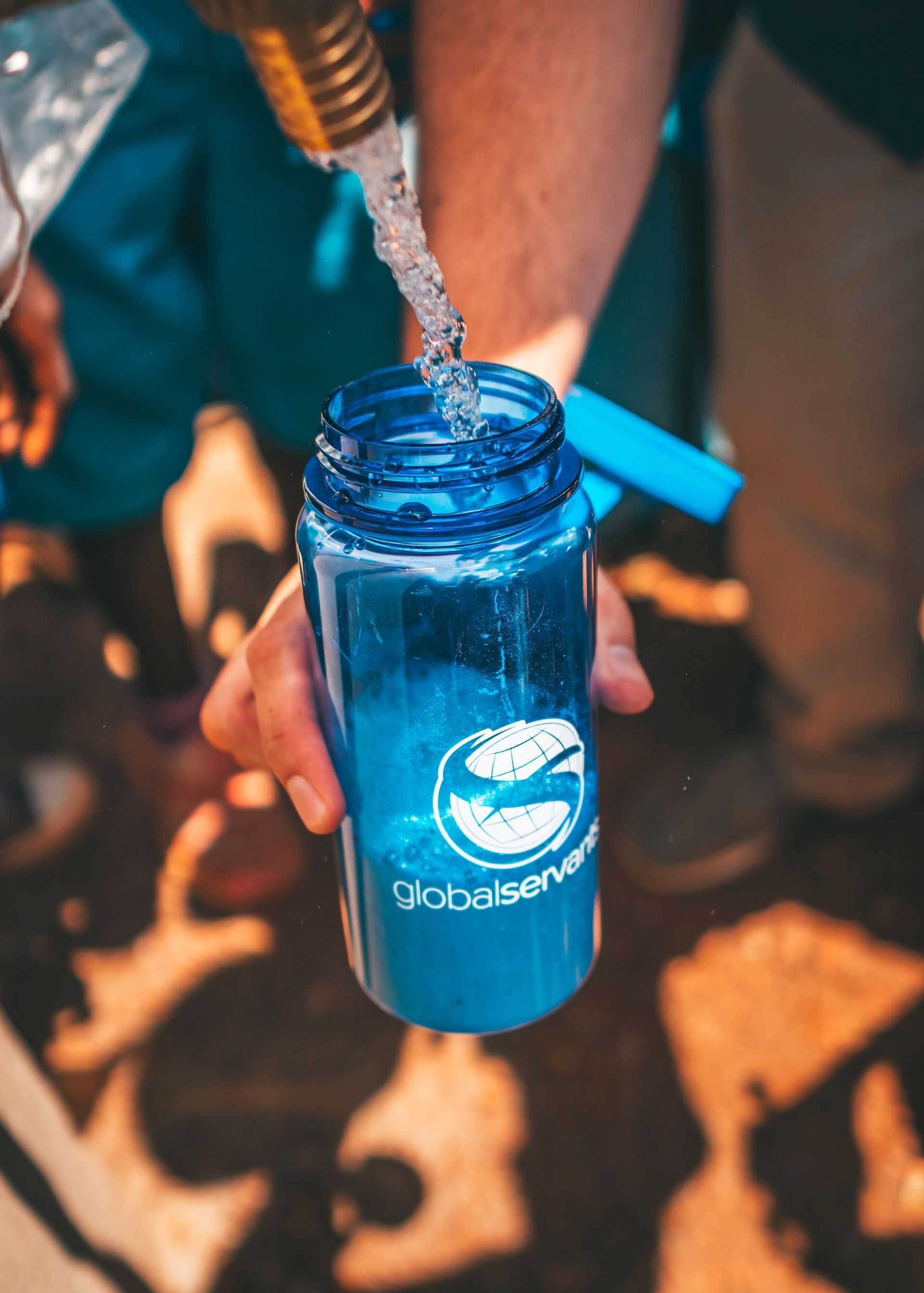 A person is pouring water into a blue globesense water bottle