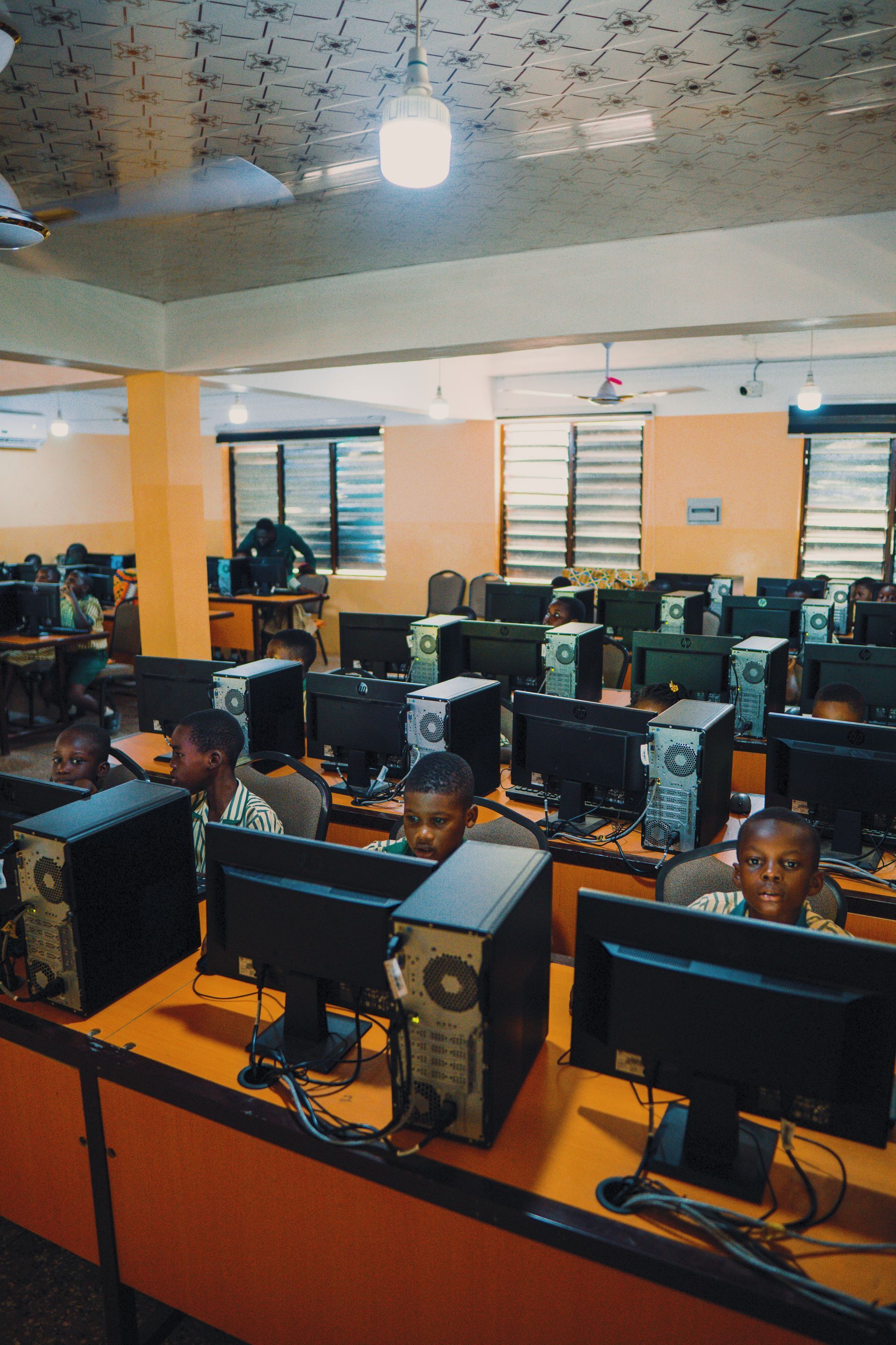 A group of people are sitting in front of computer monitors in a computer lab.