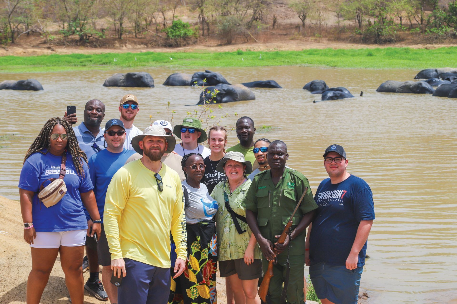 A group of people are posing for a picture in front of a body of water.