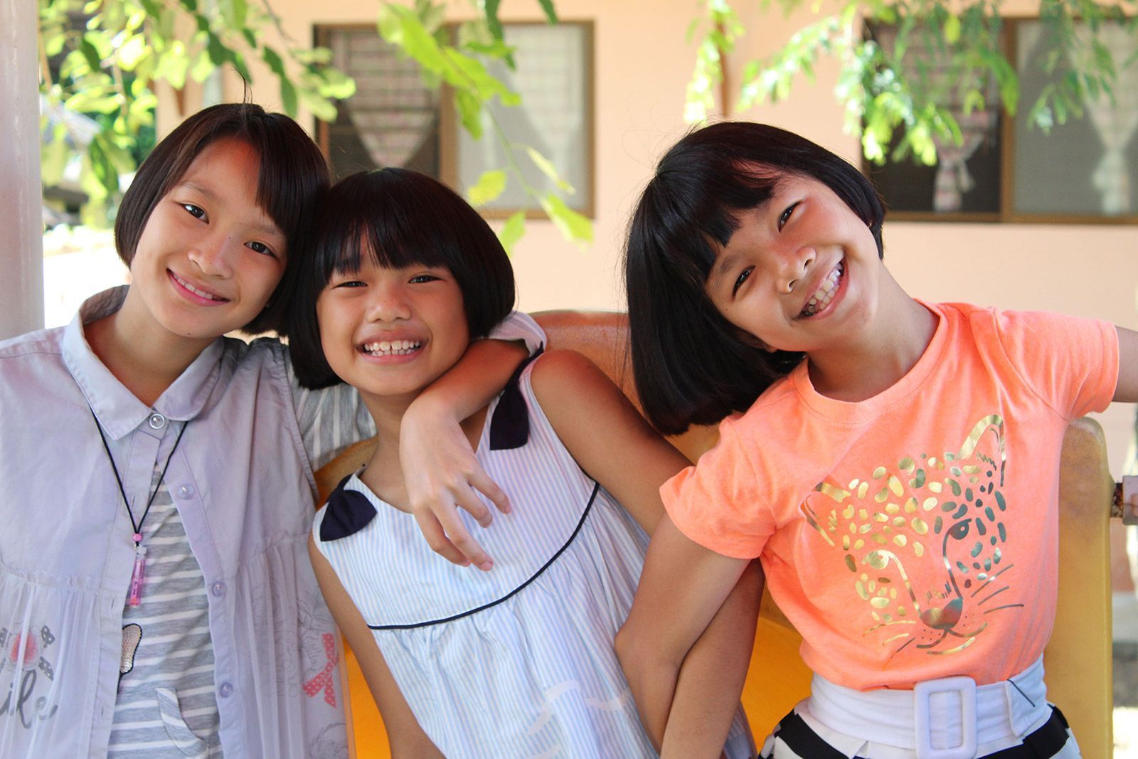 Three young girls are posing for a picture together and smiling