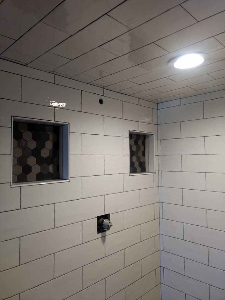 a bathroom with white tiles and a light on the ceiling