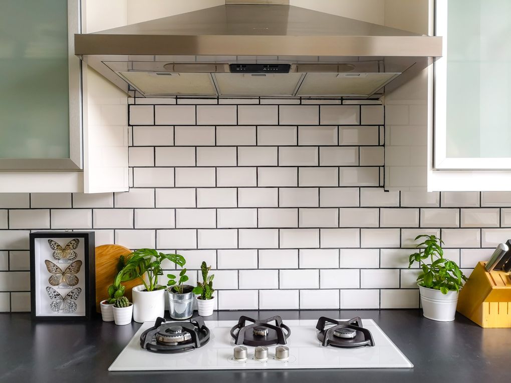 a kitchen with white tiles and a stove top oven