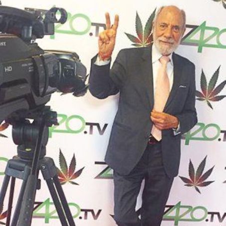 Bruce smiling and holding up the peace sign at a formal event