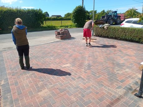 A driveway contractor sweeping a block paved driveway