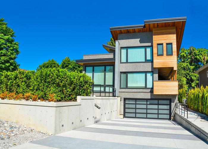 A modern house with a large garage door leading to a paved driveway in Cambridge