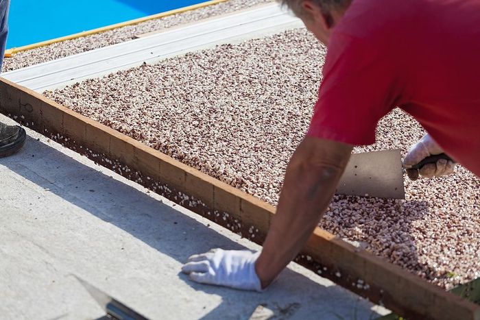 A man in a red shirt is working on a resin patio in Cambridge