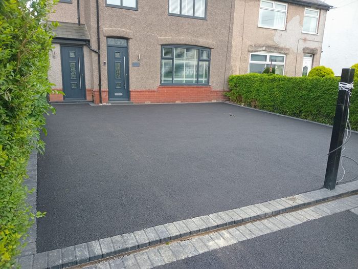 A large brick house with a black resin driveway done by Cambridge Resin driveways