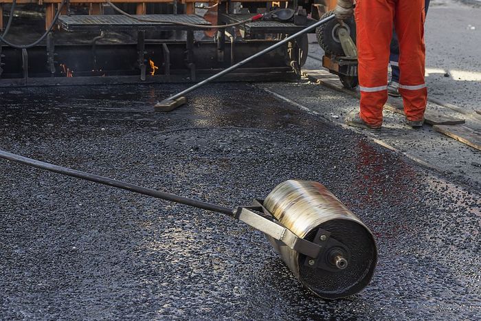 A driveway contractor rolling out the tarmac driveway in Cambridge