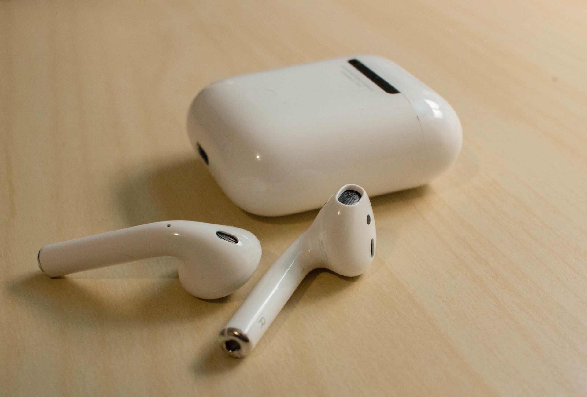 An iPhone resting next to AirPods