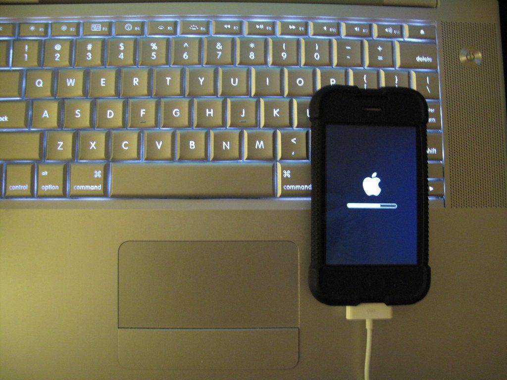 An iPhone undergoing an update, resting atop of a laptop keyboard