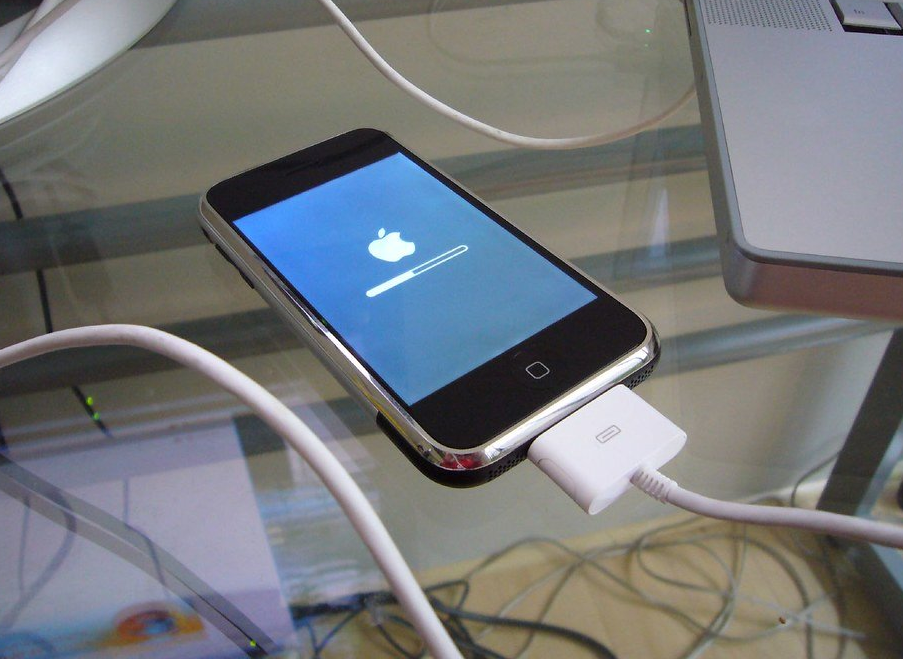 An iPhone resting atop a glass table, undergoing an update