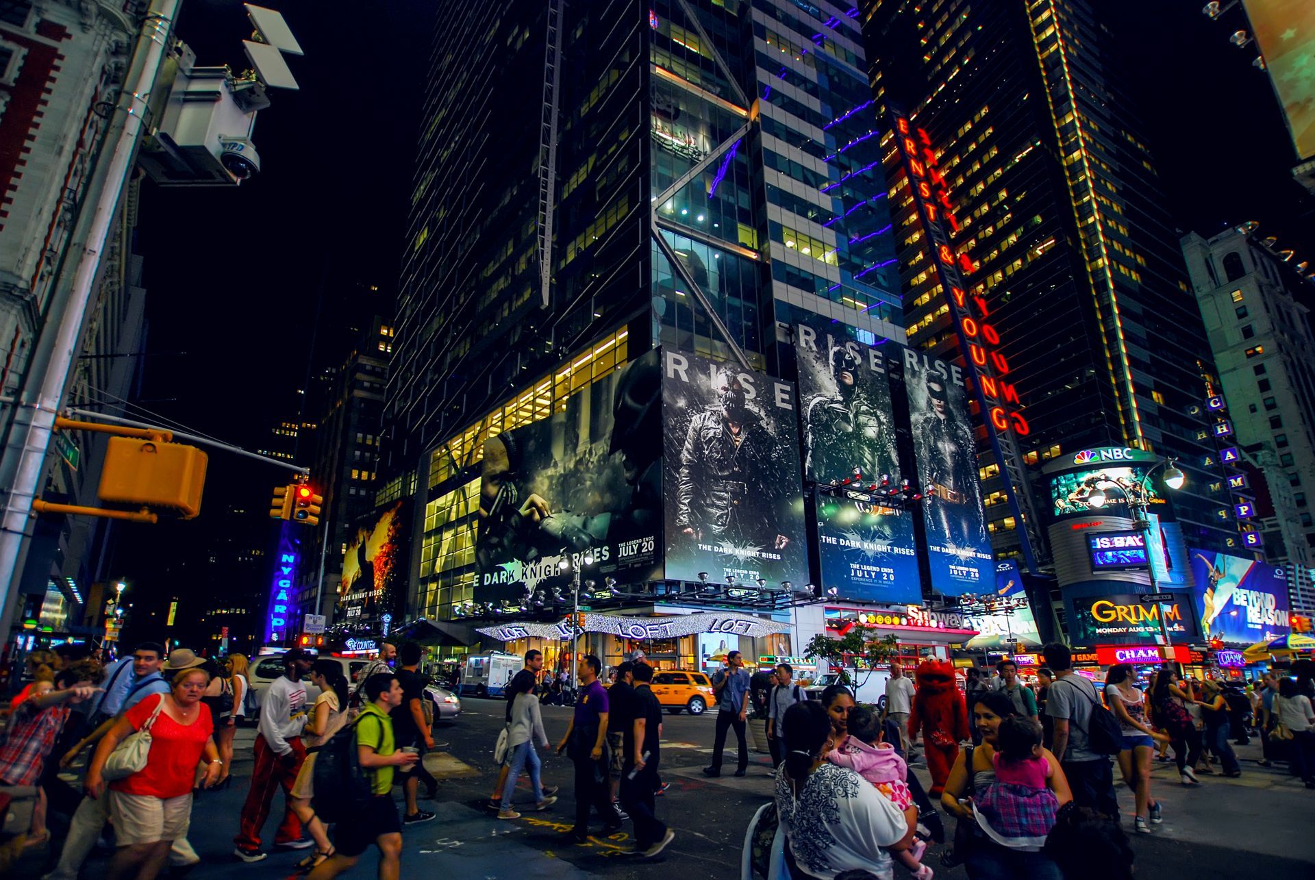 The Statue of Liberty stands on Liberty Island, with the Jersey City skyline in the background under a blue sky.