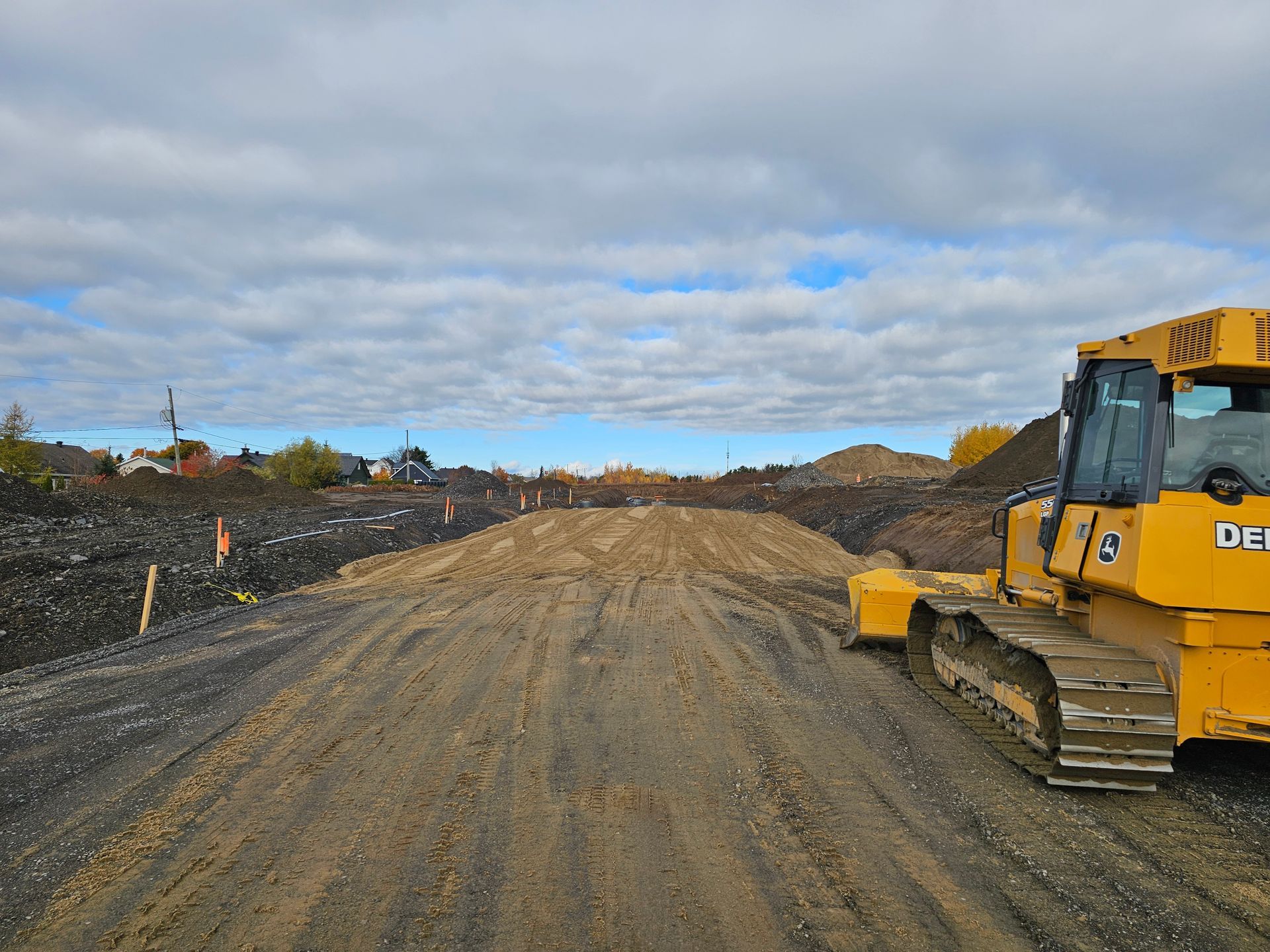 Bulldozer jaune sur un chemin de terre, sur un chantier de construction, sous un ciel nuageux