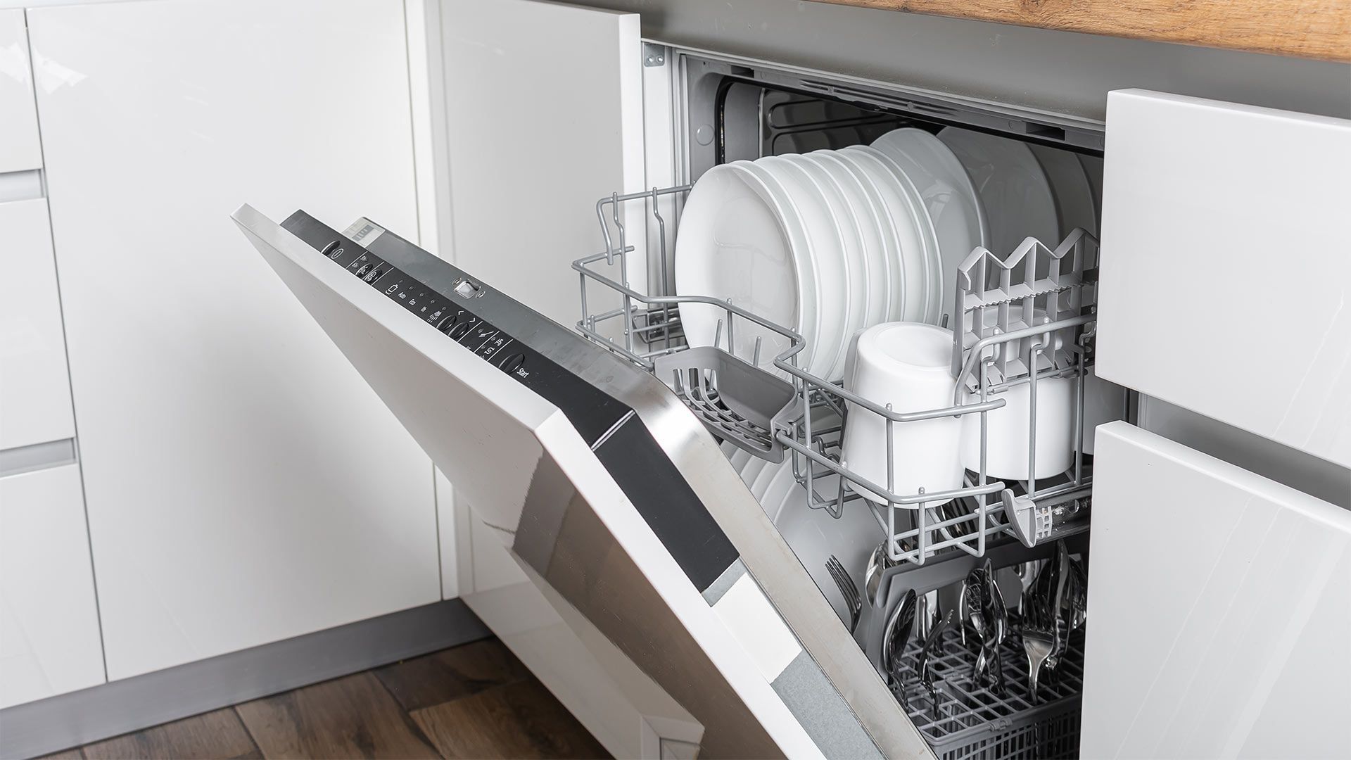 A dishwasher is filled with plates and bowls in a kitchen.