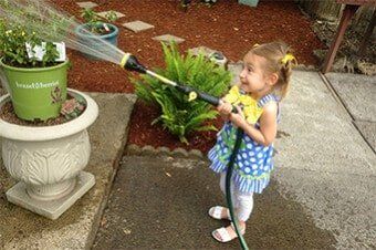 Granddaughter watering barkdust — Top-Quality Hemlock & Red Fir Barkdust In Milwaukie, OR