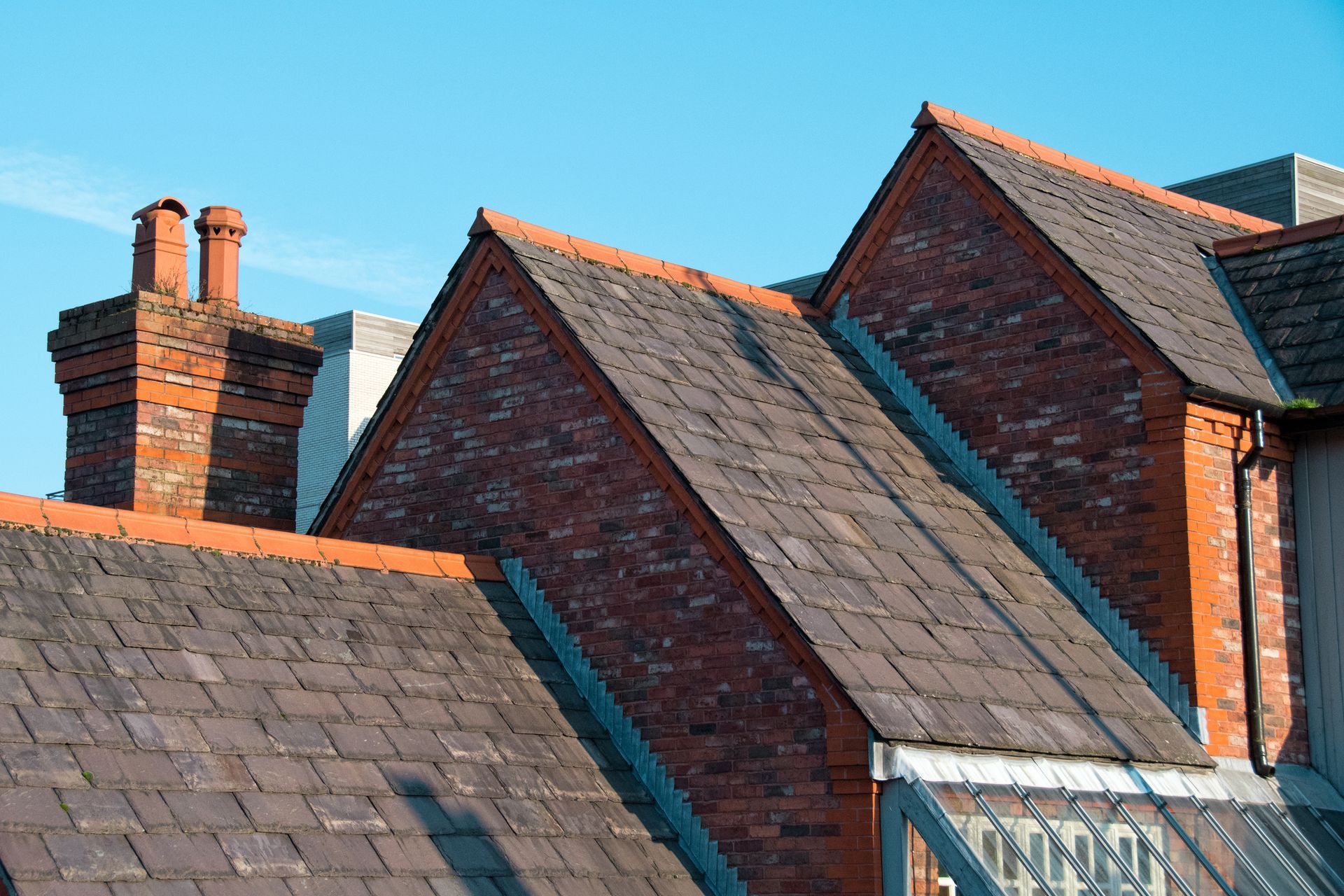 Brick rooftops and chimneys against a clear blue sky.