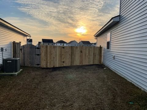 Backyard with a wooden fence gate between two white houses at sunset