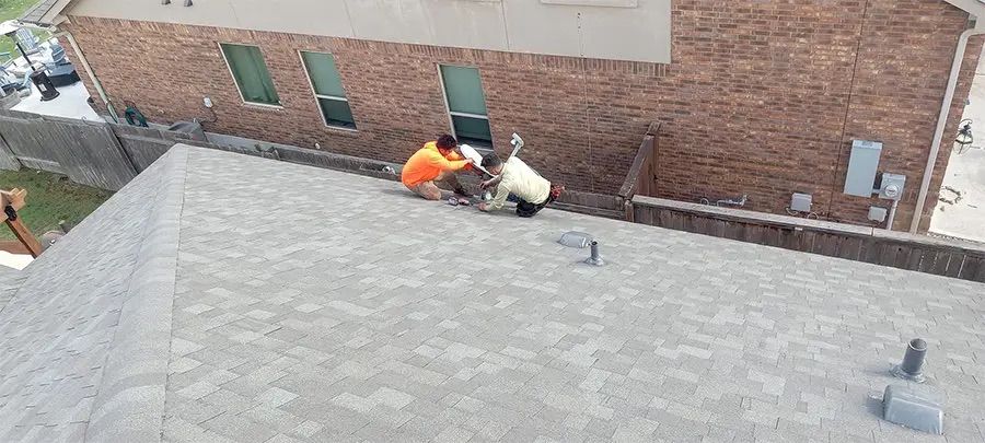 Two men are working on the roof of a house.